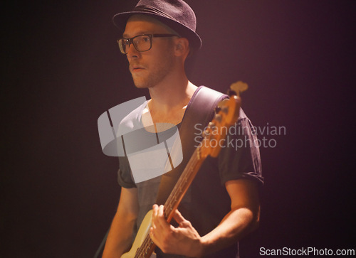 Image of Music festival, man and playing guitar for entertainment, night and artist with musical instrument. Male person, performer and equipment at concert, confident and rock star at show on black backdrop