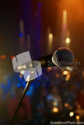 Image of Microphone, closeup and stage performance in theater with sound equipment for concert or singing. Audio, technology and light in dark room with audience for karaoke, music or event for culture