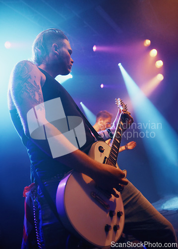 Image of Music, guitar and lighting with man on stage for concert, show or performance at festival from below. Party, event or entertainment and musician or guitarist playing instrument at musical production