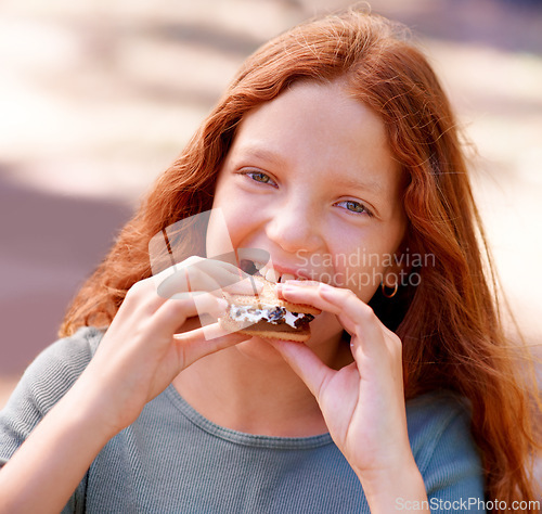 Image of Child, eating and portrait with smores outdoor, camping and relax at barbecue with dessert or cookie. Happy, girl and hungry for biscuit with marshmallow in woods or forest on holiday or vacation