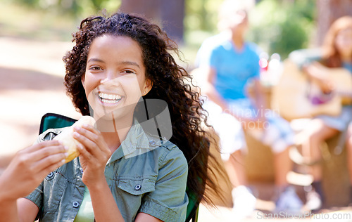 Image of Kid, eating and portrait with hotdog outdoor in camping chair and relax at barbecue with lunch. Happy, girl and hungry for food from bbq in park, woods or forest on holiday or vacation in summer
