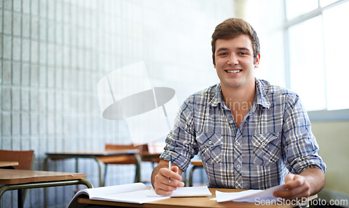 Image of Student, man and portrait in classroom for education, learning and writing of knowledge in university. Face of young and smart person with notes for college research, essay paper and studying at desk
