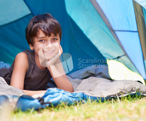 Image of Boy, kid and camping, relax in tent and summer vacation with travel and happy in portrait outdoor. Rest on sleeping bag, young child with smile and adventure in nature, childhood and recreation