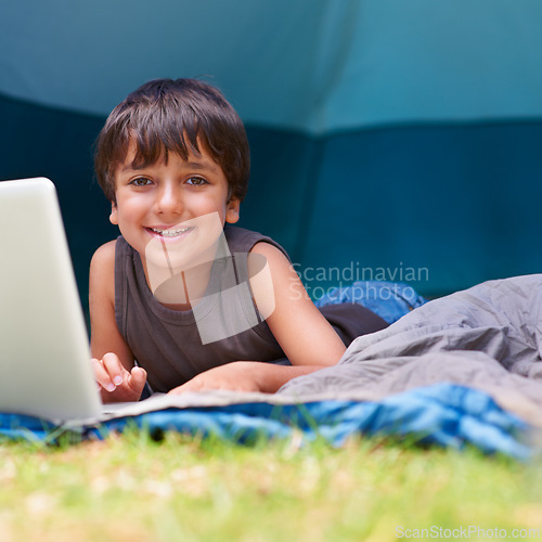 Image of Child, boy and smile with laptop in tent for camping, social media and online movie with portrait in nature. Person, face and kid or happy outdoor on grass for gaming, vacation relax or holiday fun