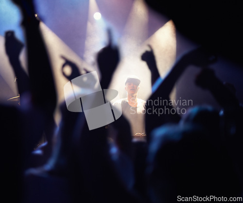 Image of Concert, audience and dj music with hands from people at rock, band and festival event at a stage with lights. Night show, dance and party with crowd with rave, techno and entertainment at venue