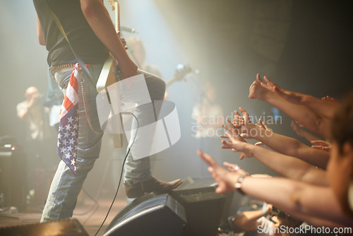 Image of Rock concert, crowd and guitarist on a stage, fans and performance with music festival or audience. Event, people or artist with a band or group reaching for famous person or sound with live musician