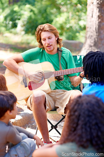 Image of Nature, camp and man playing guitar for entertainment, talent or music in woods or forest. Singing, musician and male person with acoustic string instrument outdoor in park or field on weekend trip.