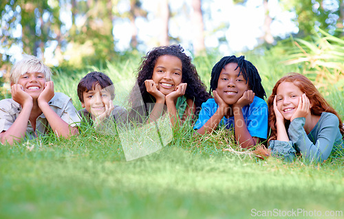 Image of Nature, smile and portrait of children on grass in outdoor park, field or garden together. Happy, diversity and group of excited young kids relaxing and laying on lawn in woods or forest for summer.