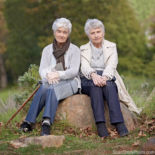 Image of Senior friends, portrait or outdoor in nature on rock, together or bonding on retirement on holiday. Elderly women, serious or face on trip in countryside, winter or care for person with disability