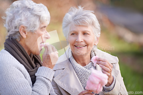 Image of Senior women, eating and snack in nature with candy floss, together and relax on retirement outdoor. Elderly friends, happy and junk food on vacation in countryside, bonding and social in park