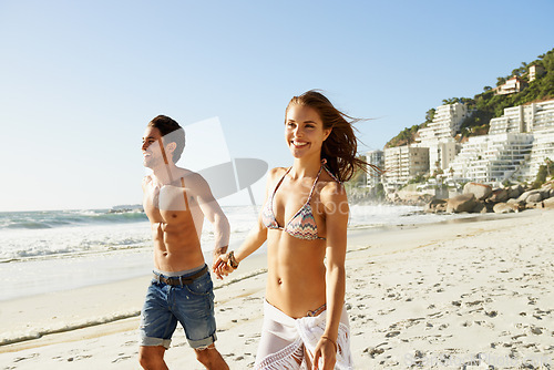 Image of Holding hands, love and couple walking at a beach with smile, fun and bonding in nature together. Travel, fun and happy people at sea for summer, romance or anniversary vacation in South Africa