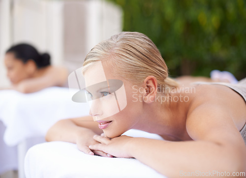 Image of Luxury, woman and relax on massage bed with smile for wellness, zen and beauty treatment for body care. Person, daydreaming and physical therapy at resort, salon table and spa on holiday or vacation