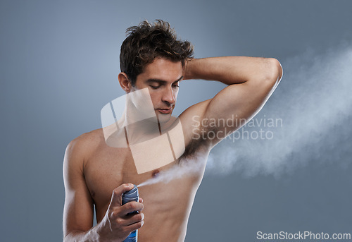 Image of Man, deodorant and spray for healthy odor in studio or product application for clean smell, hygiene or grey background. Male person, topless and confidence or armpit wellness, care or mockup space