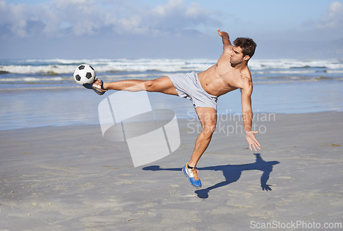 Image of Man, beach and kicking soccer ball for game, sports or exercise in outdoor hobby, training or practice. Young muscular male person or football player in match or cardio workout by ocean coast or sea