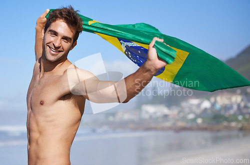 Image of Man, brazil flag and portrait for happiness at beach, outdoor fun and happy in summer on vacation. Young person, face or holiday by sea in freedom or soccer competition by ocean for travel adventure