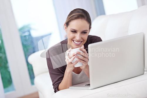 Image of Coffee, happy woman and laptop on a sofa for streaming movie, film or online video home. Face, smile and female person relax in a living room with pc, tea or social media, subscription or service