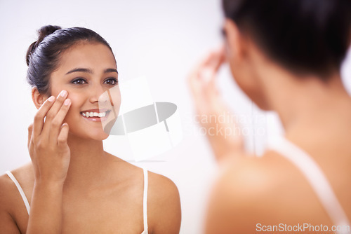Image of Happy woman, face and cream in mirror for beauty, cosmetics or makeup in bathroom at home. Female person or model smile applying lotion or moisturizer for facial, skincare or treatment in reflection