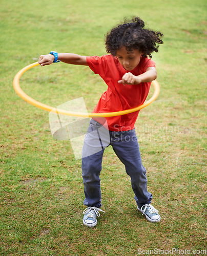 Image of Child, playing and hula hoop on field on vacation, green grass and sunshine with happiness in city. Young boy, mexican and game on playground, summer holiday and leisure with wellness in urban town