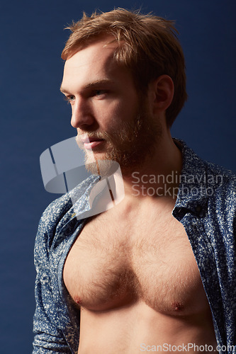 Image of Fashion, thinking or model with chest in studio on a blue background wearing an open unbuttoned shirt. Ginger, body or handsome male person posing on color wall for masculine style, health or fitness