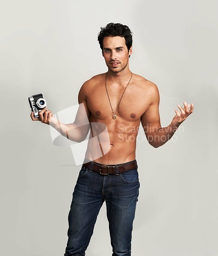 Image of Camera, shirtless and portrait of man in a studio with art, creative and photography career. Confused, doubt and young male photographer from Canada with dslr equipment isolated by gray background.