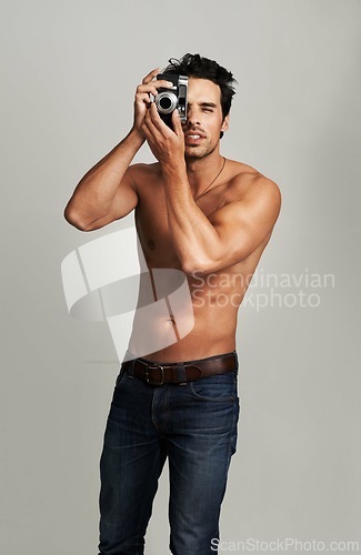 Image of Camera, shirtless and young man in a studio with art, creative and photography career. Confused, doubt and attractive male photographer from Canada with dslr equipment isolated by gray background.