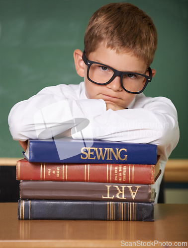 Image of Frustrated boy child, books and portrait in classroom for knowledge, information and studying at academy. Student kid, learning and education with glasses, angry and stress for assessment at school