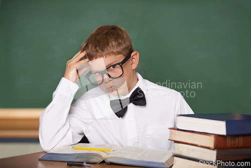 Image of Student child, stress and portrait with books, classroom and anxiety for exam, assessment and studying for knowledge. Boy kid, notebook and learning for education, development and glasses at table