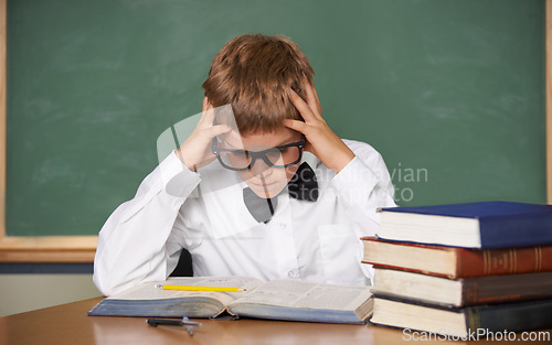 Image of Boy child, stress and thinking with books, classroom and anxiety for exam, assessment and studying for knowledge. Student kid, notebook and learning for education, development and reading at table