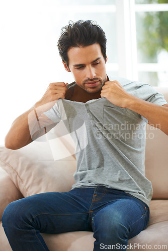 Image of Sofa, man and take off tshirt in a house for comfort, rest or chilling on weekend, day off or vacation. Sweater, removal or male person in a living room undressing, relax and ready to be comfortable