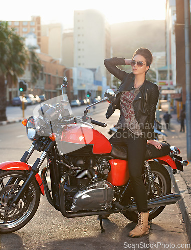 Image of Bike, fashion and woman in city with sunglasses for travel, transport or road trip as rebel. Leather, asphalt and model with attitude on classic or vintage motorcycle for transportation or journey