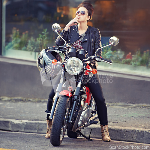 Image of Motorcycle, leather and smoke with woman in city for travel, transport or road trip as rebel. Fashion, cigarette and sunglasses with model on classic or vintage bike for transportation or journey
