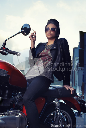 Image of Motorcycle, cigarette and woman smoking in city for travel, transport or road trip as rebel. Fashion, tobacco or nicotine and biker with attitude on classic or vintage bike for urban journey
