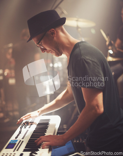 Image of Concert, musician and man on piano at stage for performance, rock band or audio at music festival. Artist, professional or play on electric keyboard, synthesizer instrument or sound for entertainment