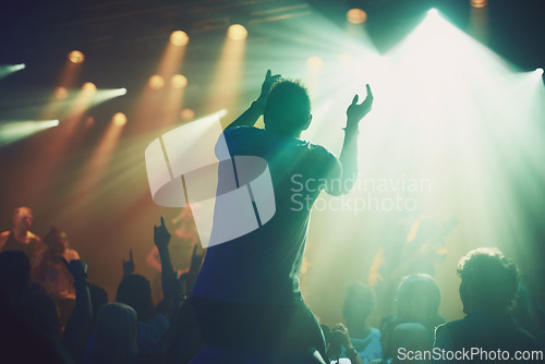 Image of Back, dark concert and person clapping at music performance and having fun. Social event, party and excited fan cheering for live show culture on new year eve with a crowd at the disco celebrating