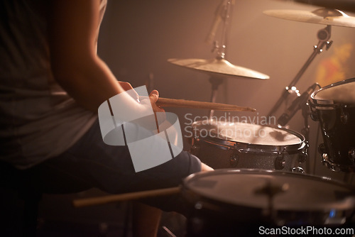 Image of Hands, drummer and musician in performance at rock concert, music festival on stage and band. Closeup, artist and playing on drumstick for entertainment, sound or rehearsal on percussion instrument