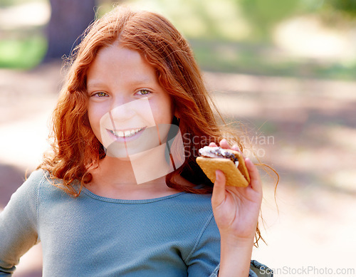 Image of Young girl, camping and smores in portrait in nature, happiness and hungry for sweet snack in woods. Red hair, child and happy face by sugar candy for eating, relax and outdoor on holiday adventure