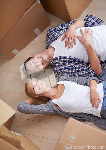 Image of Couple, floor and moving or boxes for relax from packing or real estate property or bonding, marriage or apartment. Man, woman and rest for investment loan or mortgage for relocation, rent or buy