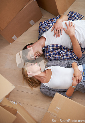 Image of Couple, floor and moving boxes or rest from packing or real estate property for bonding, marriage or apartment. Man, woman and relax for investment loan or mortgage for relocation, rent or new home