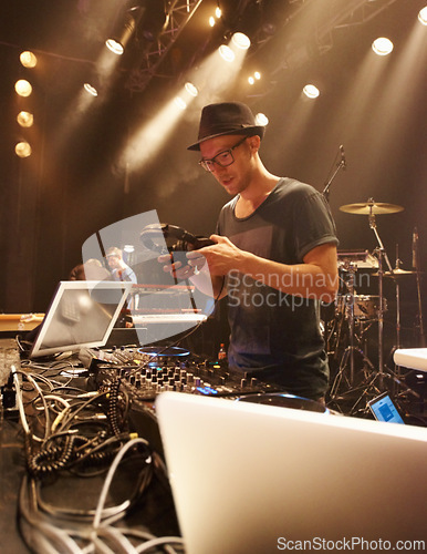 Image of Music, DJ and spotlight on man at stage with headphones and equipment for performance on sound board. Techno, musician and person in club at night mixing on turntable with technology for rave