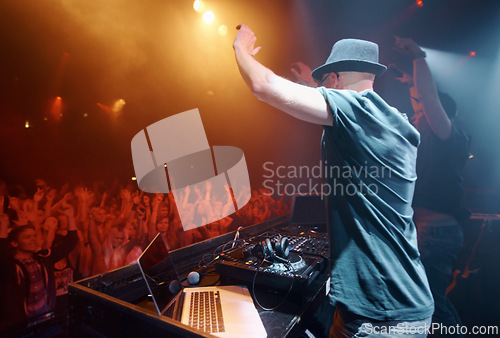 Image of Concert, party or man in music festival to dj for performance or celebration with fans or audience. Stage, night or musician with hand up or crowd of people at a rave event with turntable technology