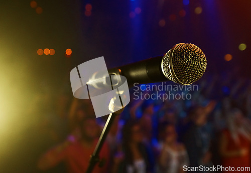 Image of Closeup, microphone and stage performance in theater with audience and sound equipment for concert or singing. Audio, technology and light in dark room with crowd for open mic, karaoke or music event