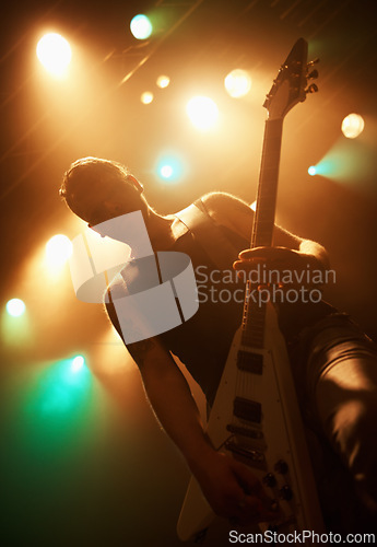 Image of Concert, band and guitar with man on stage for music, performance and rock show. Event, spotlight and energy with male musician playing instrument at festival club for rave, disco and celebration
