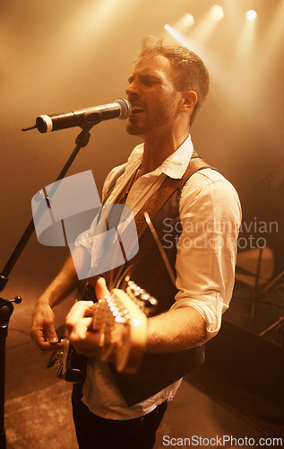 Image of Singer, music and guitar with man on stage for concert, performance and rock show. Event, spotlight and energy with male musician playing instrument at festival club for rave, disco and celebration