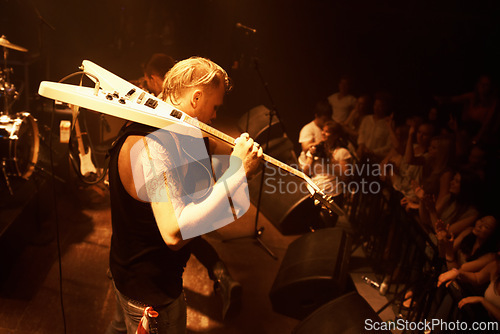 Image of Guitar, musician and stage concert at night with man in performance of rock or metal music. Festival, event and rocker playing for crowd with talent or dance in theater and club with light and energy