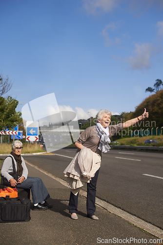 Image of Women, road and hitch hiker for travel in retirement, lift and friends in city with bags for adventure. Senior ladies, thumbs up and happy by roadside with hand gesture and stop transport to commute