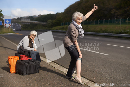 Image of Women, road and funny hitch hiker for travel in retirement, lift and senior friends in city with bags for adventure. Elderly, thumbs up and tired by roadside with comic and stop transport to commute