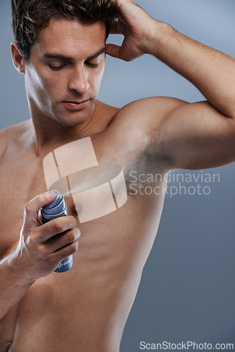Image of Man, deodorant and spray for armpit odor in studio or product application for clean smell, hygiene or grey background. Male person, topless and confidence or health wellness, care or mockup space