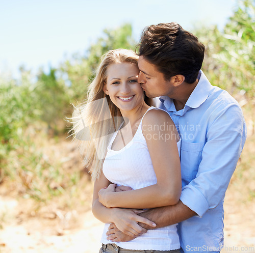 Image of Couple, portrait and happy in nature with kiss in relationship for holiday, vacation or travel. Romance, man and woman with smile outdoor in forest with embrace for bonding, love or relax in woods