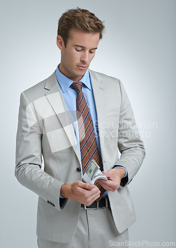 Image of Businessman, face and dollar or finance in studio for money laundering, white collar crime or investment. Cash, entrepreneur and person with stealing and fraud at corporate job on gray background