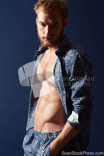 Image of Fashion, thinking or ginger model with body in studio on a blue background wearing an open unbuttoned shirt. Man, abs or handsome male person posing on color wall for masculine style with six pack